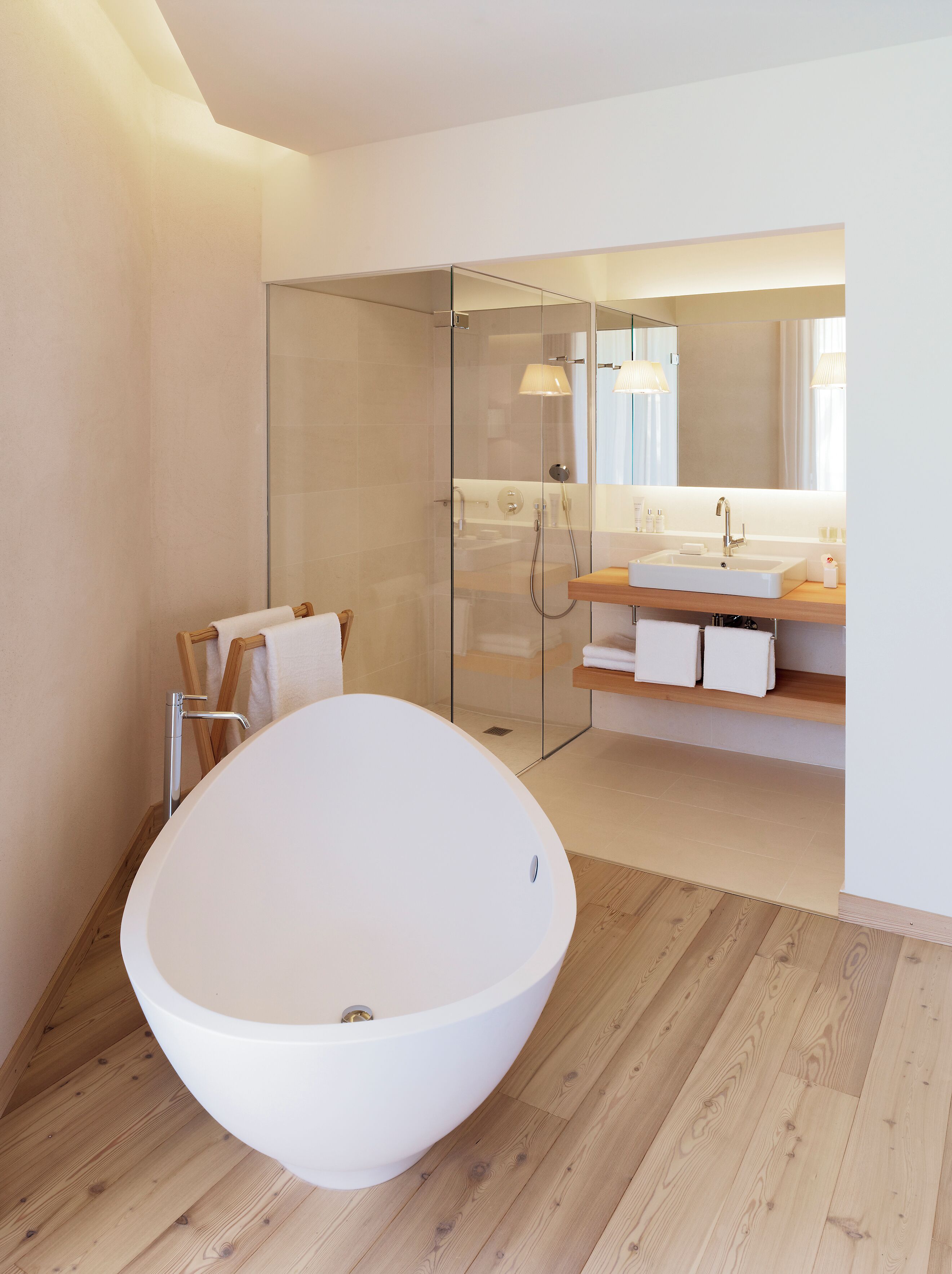 A modern bathroom with a freestanding bathtub, a glass-enclosed shower, and a vanity with a mirror.