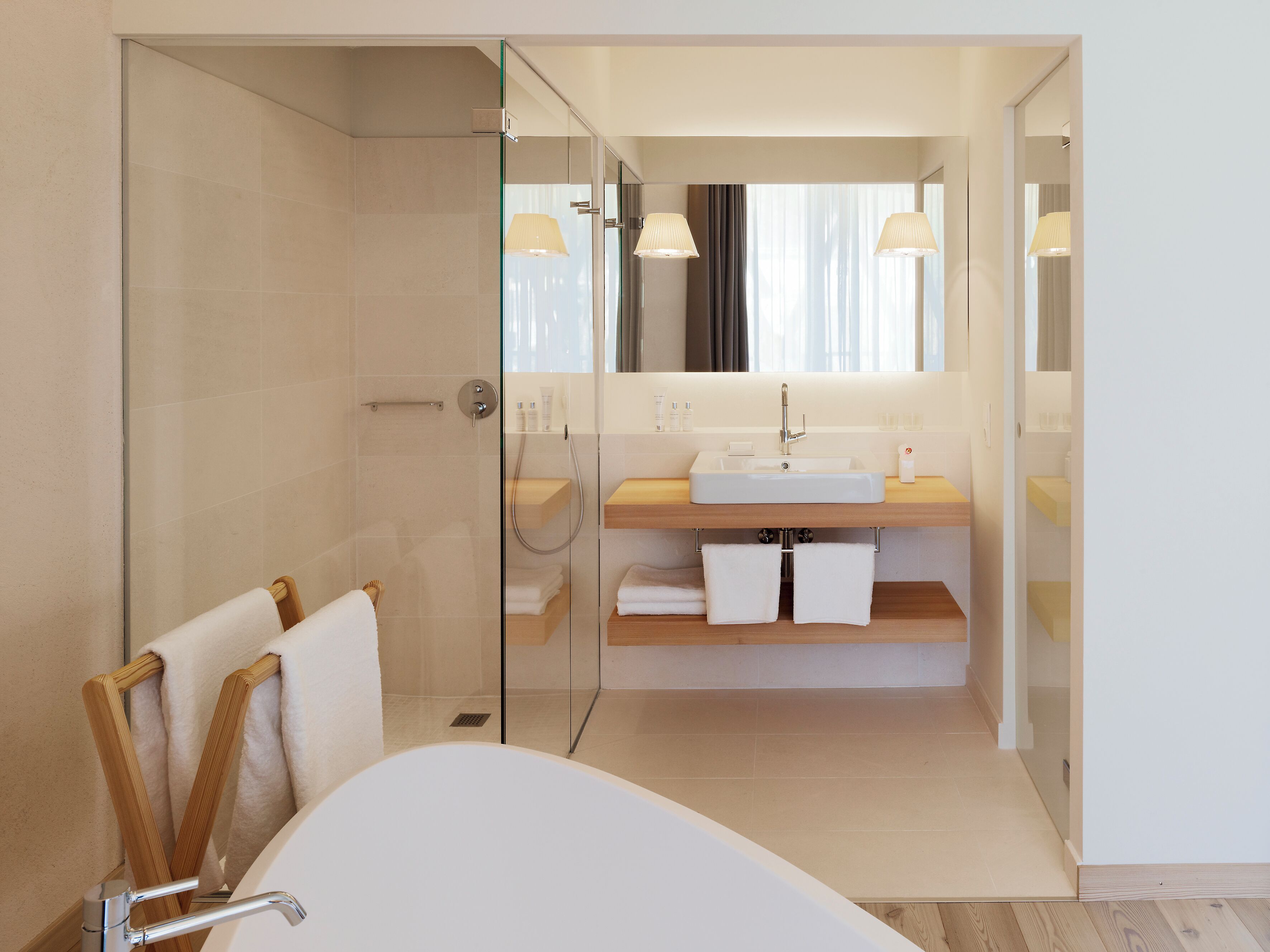 A modern bathroom with a glass shower enclosure, a freestanding bathtub, and a vanity with a mirror.