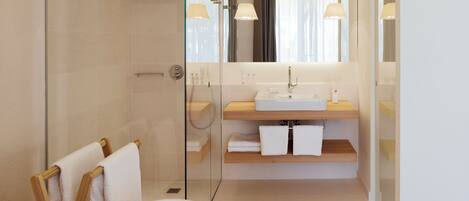 A modern bathroom with a glass shower enclosure, a freestanding bathtub, and a vanity with a mirror.