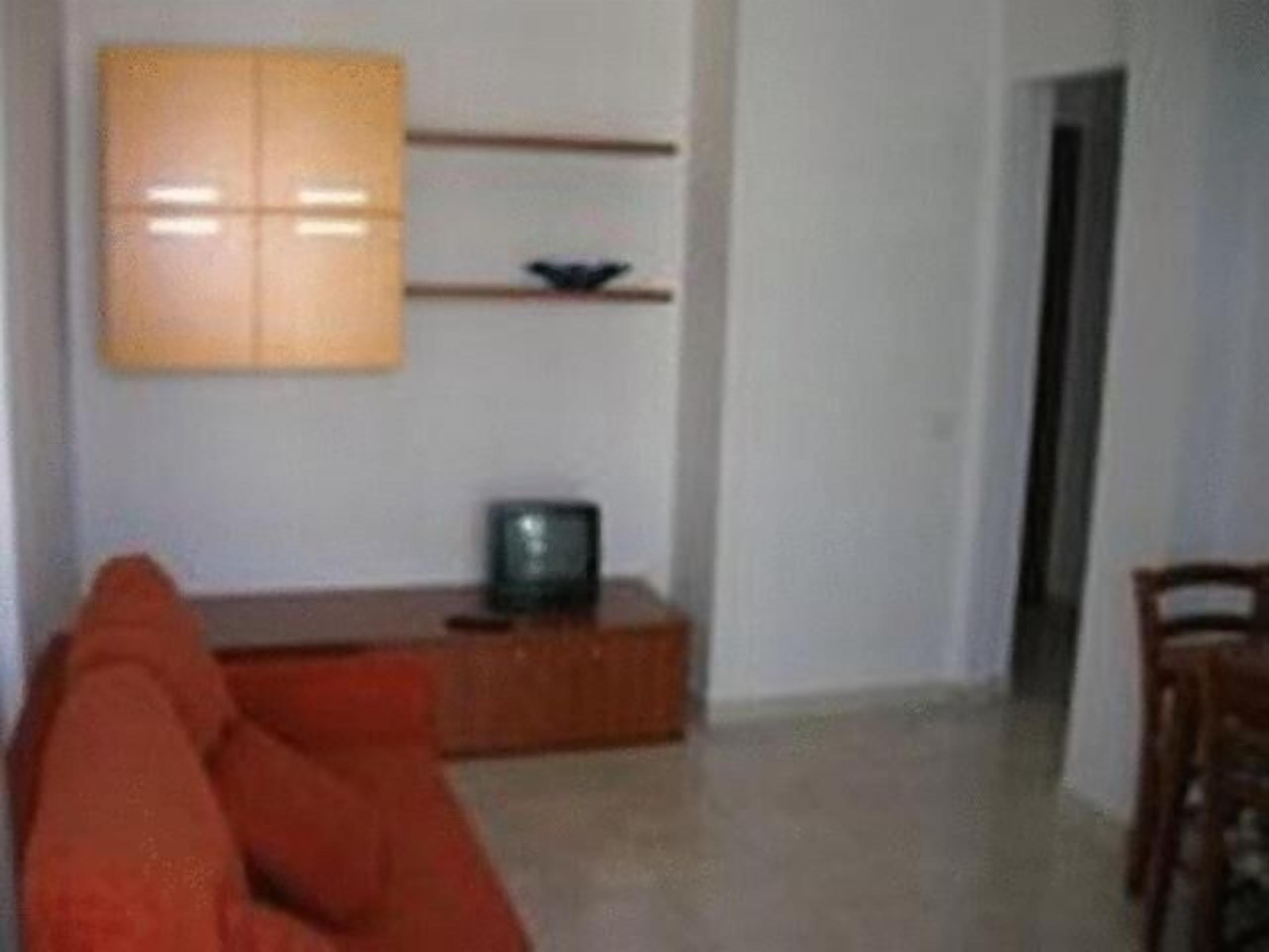 A living room with a sofa, a TV on a stand, and a cabinet.