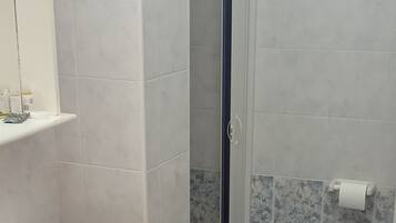 A bathroom with a shower, two sinks, and a toilet.