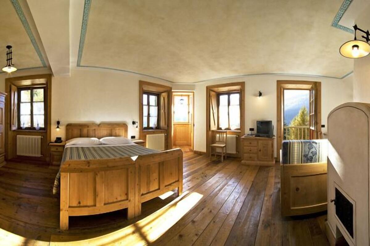 Ein gemütliches Schlafzimmer mit einem Holzbett, einem Schminktisch, einem Fernseher und einem Kamin.