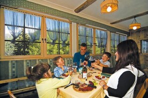 Un comedor con ventanas amplias, una mesa dispuesta para una comida y una araña.