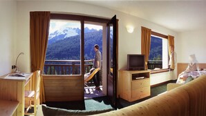 Una habitación de hotel con balcón, televisión, cama y escritorio.