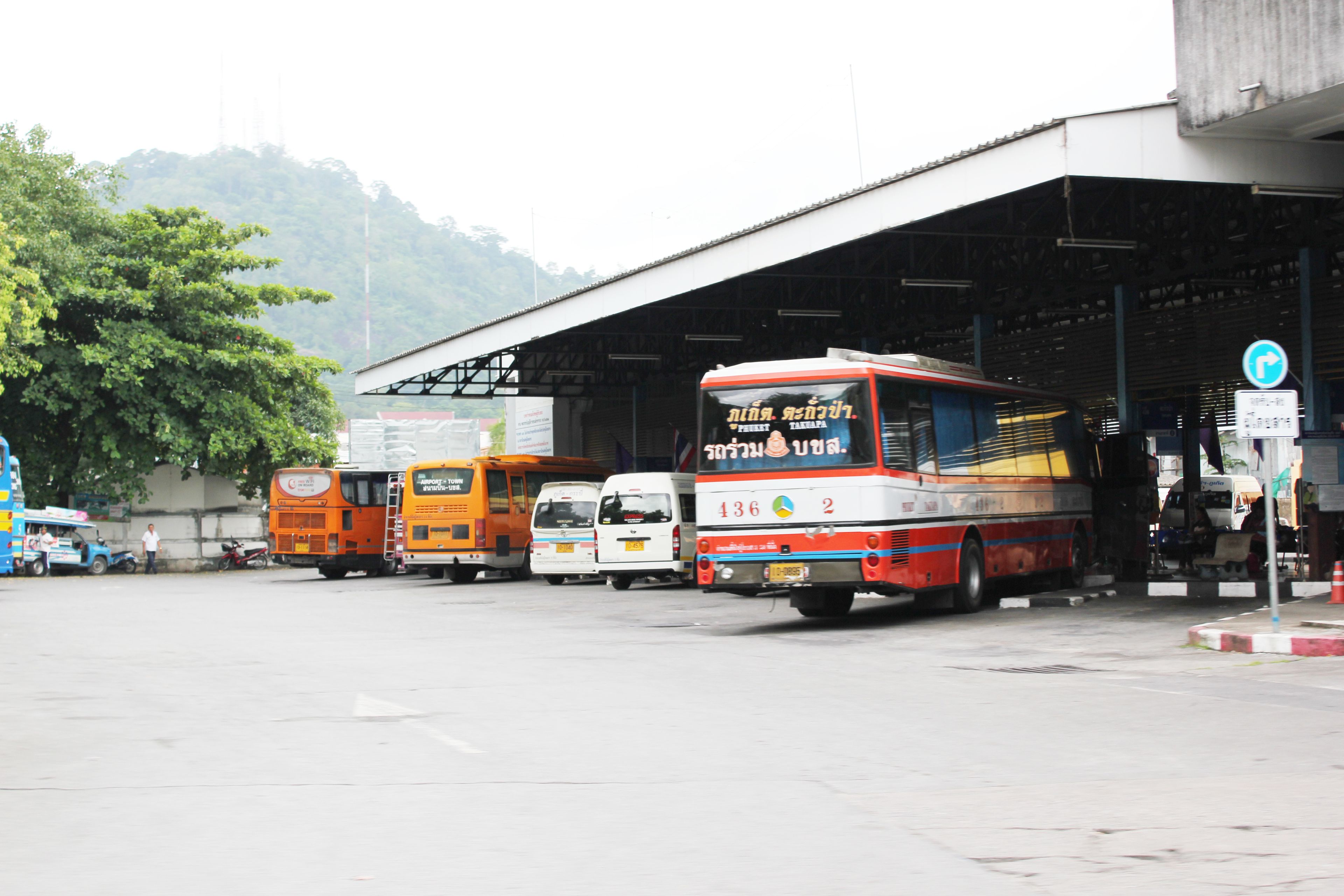 A bus station with multiple buses parked under a covered area.