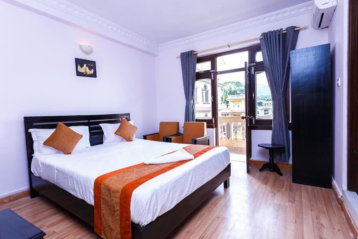 Una habitación de hotel con una cama grande, una mesita y vistas a la ciudad desde la ventana.