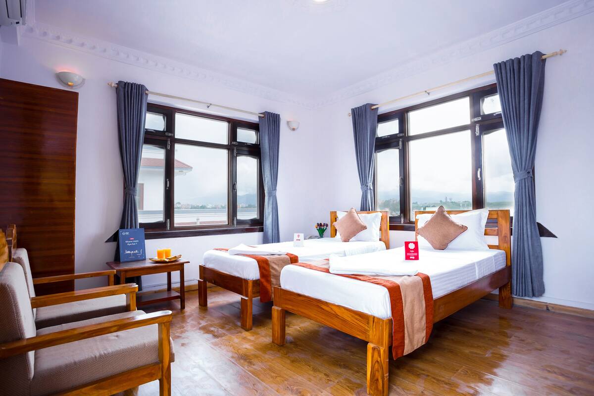 Una habitación de hotel con dos camas de madera, un escritorio de madera y una silla.
