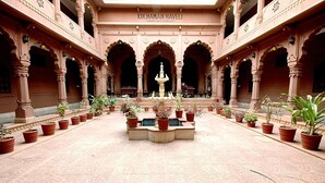 A spacious courtyard with a central fountain, surrounded by potted plants and architectural arches. - Kuchaman Haveli (Jodhpur)