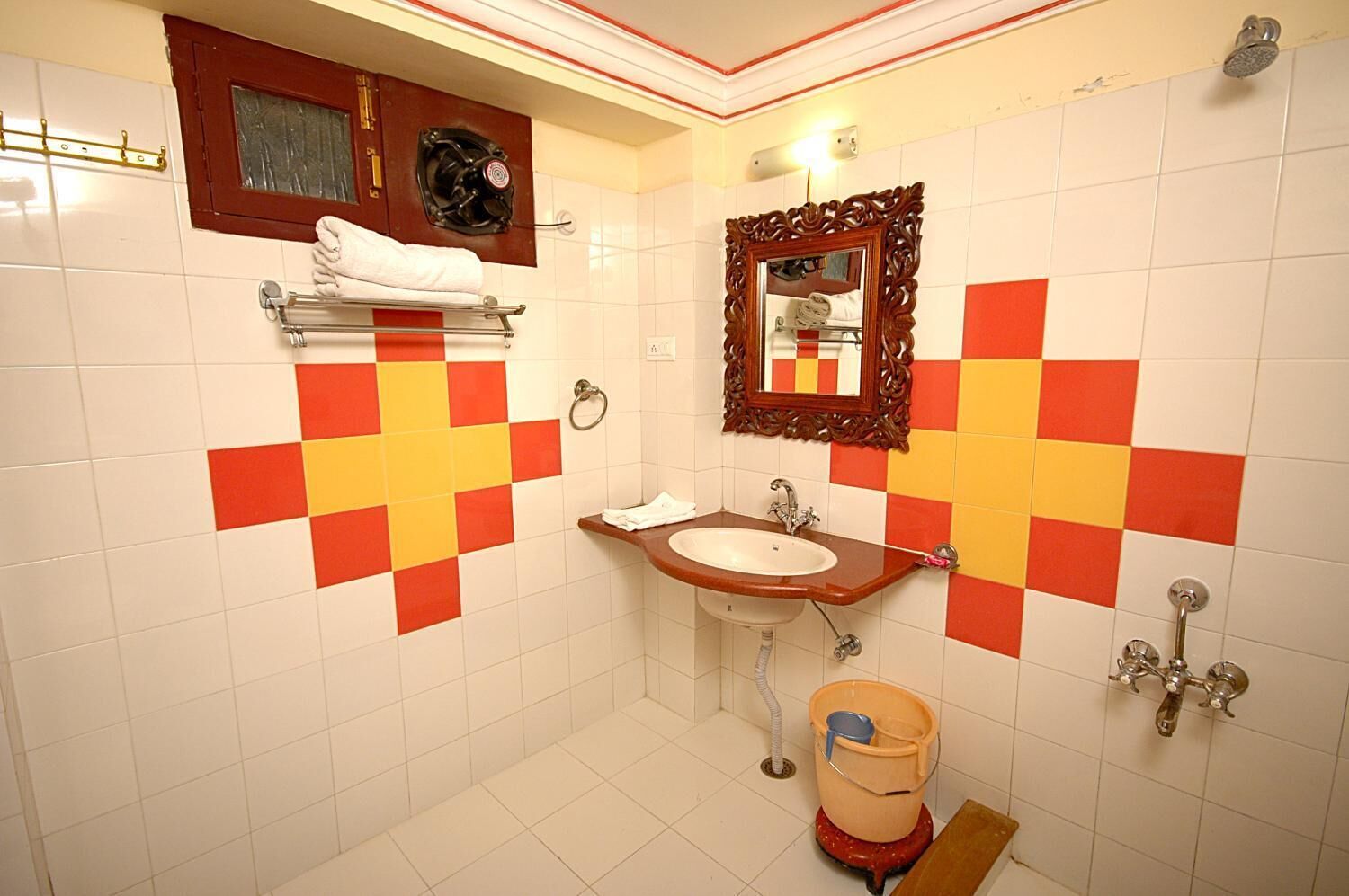 A bathroom with a sink, mirror, and a red and yellow checkered wall design.