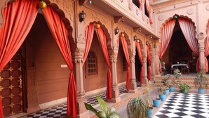A traditional building with red curtains, checkered flooring, and columns. - Kuchaman Haveli (Jodhpur)