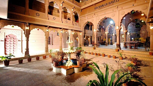 A spacious courtyard with ornate arches, a central fountain, and potted plants. - Kuchaman Haveli (Jodhpur)