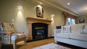 Una sala de estar con chimenea, un sofá, dos sillones estampados y una alfombra.