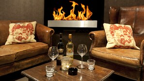 Una sala de estar acogedora con sofás de cuero, una chimenea y una mesa con vasos y botellas.