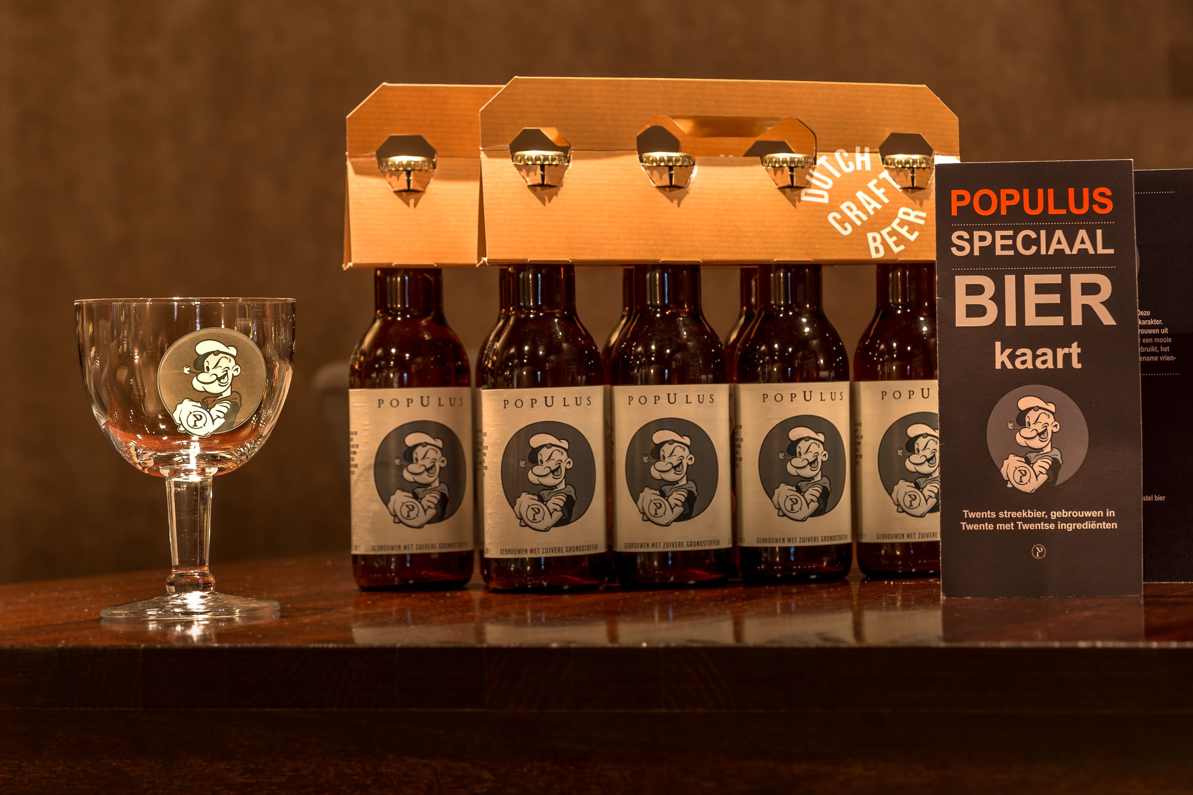 Un vaso con un personaje de caricatura, una docena de cerveza Populus y una tarjeta promocional.