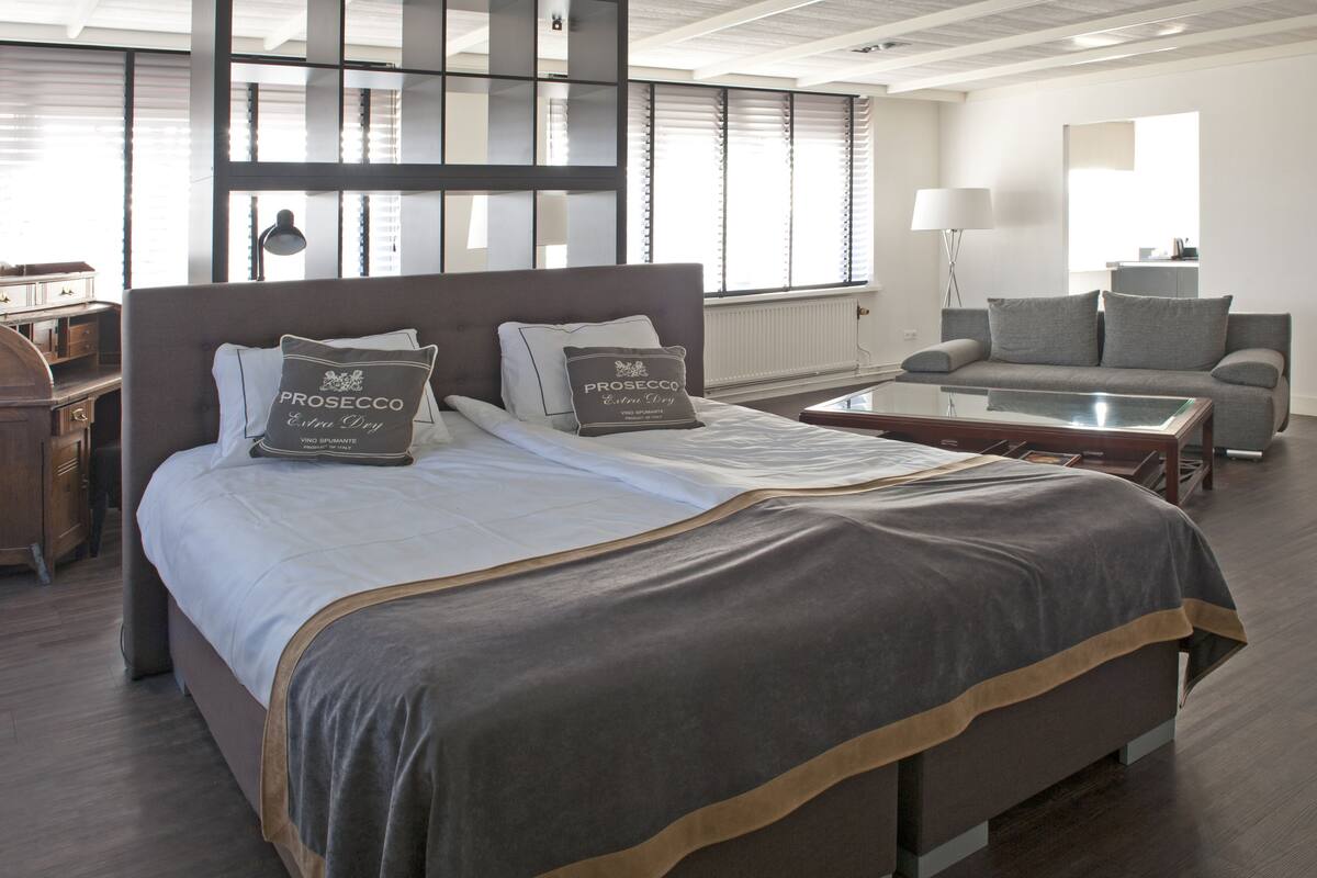 Una habitación de hotel moderna con una cama grande, un sofá, una mesita de centro y un escritorio.