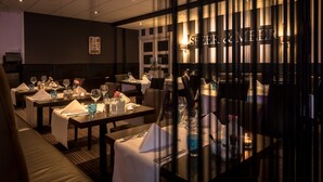 Un restaurant avec des tables dressées pour le service, un coin bar et une enseigne sur laquelle on peut lire : « SF EER & MEER ».