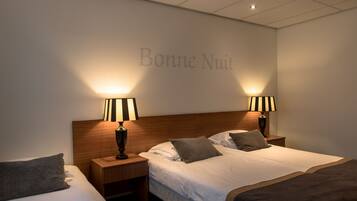 Une chambre d’hôtel avec deux lits, des tables de chevet, des lampes et un mur sur lequel est écrit « Bonne nuit ».