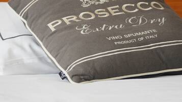 A bed with a pillow labeled "PROSECCO Extra Dry" and a tag indicating it is a product of Italy.