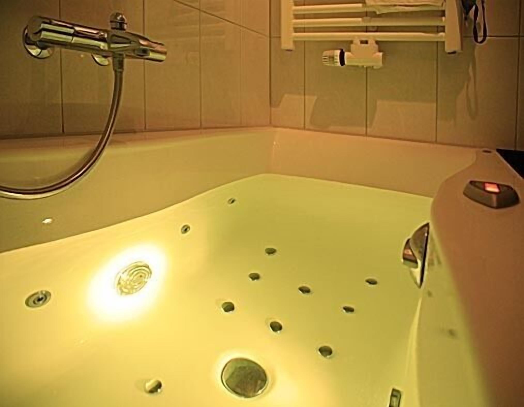 A bathtub with a handheld showerhead, a control panel, and a towel rack.