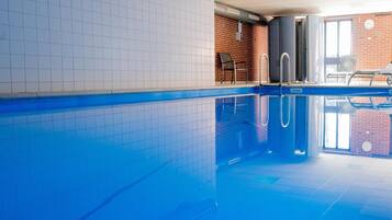 An indoor swimming pool with tiled walls and a clear blue pool.