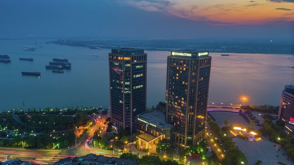 Two high-rise buildings with illuminated windows and a view of a river with boats. - DoubleTree by Hilton Hotel Wuhu (Wuhu)