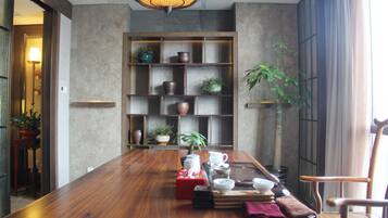 Un comedor con una mesa de madera, estantes con objetos decorativos y una planta en maceta.