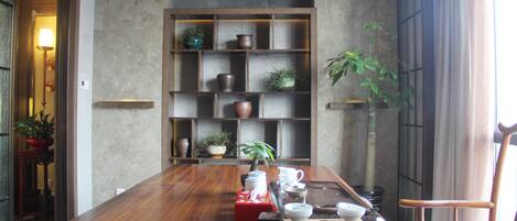 A dining area with a wooden table, shelves with decorative items, and a potted plant.