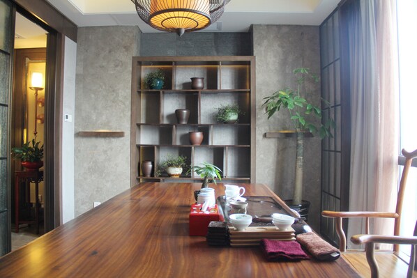 Un comedor con una mesa de madera, estantes con objetos decorativos y una planta en maceta.