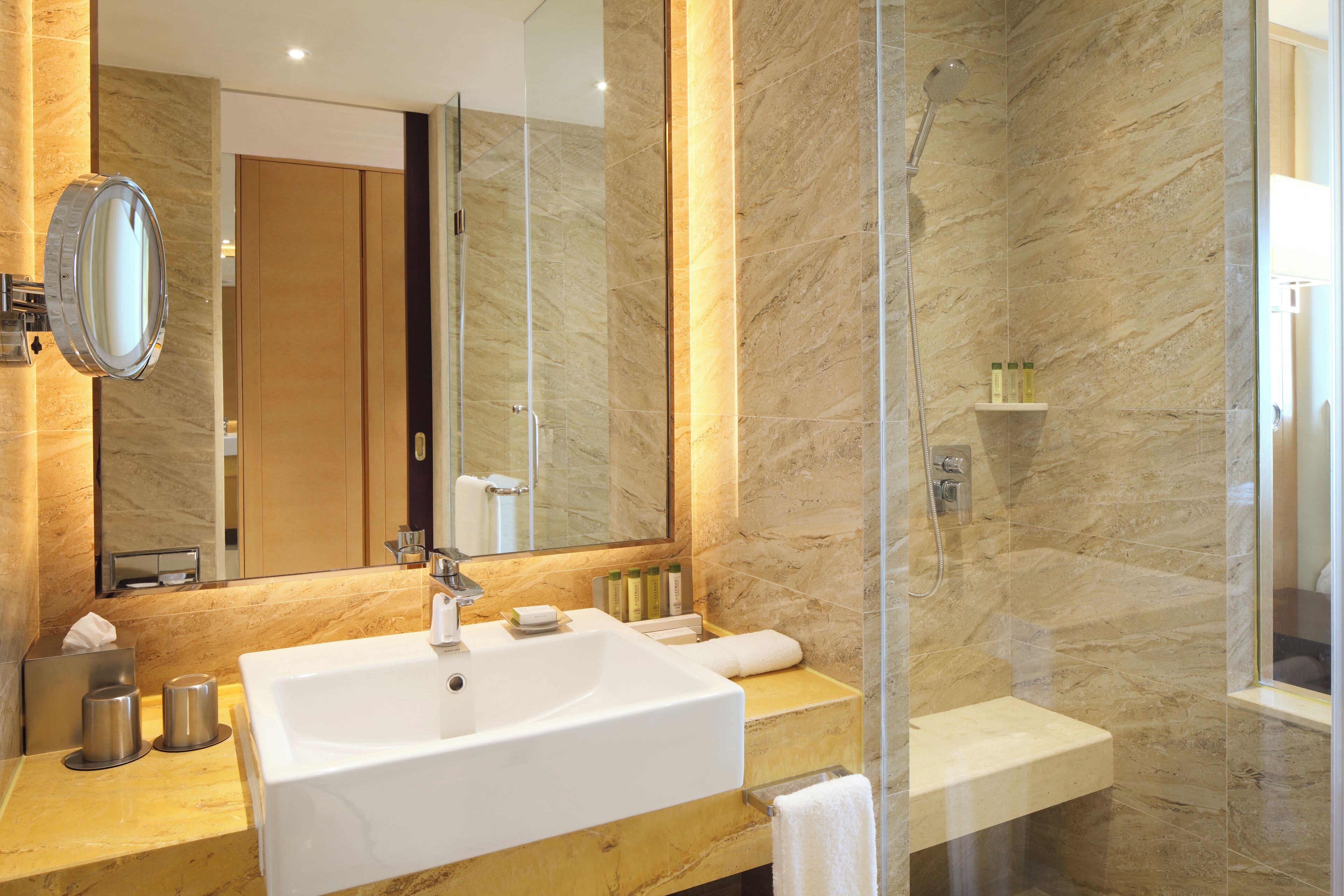 Un baño moderno con un lavamanos grande, espejo e inodoro con ducha.