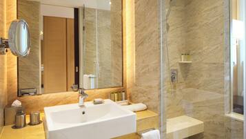 Un baño moderno con un lavamanos grande, espejo e inodoro con ducha.
