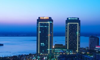 Dos edificios altos con letreros iluminados, uno con la leyenda "SHIMA" y el otro "DOUBLETREE".