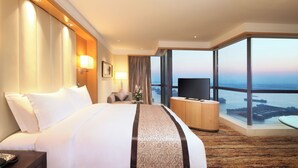 Habitación de hotel con una cama grande, televisión, escritorio y vistas a la ciudad.