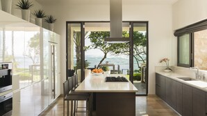 A modern kitchen with a large island, glass doors leading to a balcony with a view of the sea. - Residences at Dorado Beach, a Ritz-Carlton Reserve (Dorado)