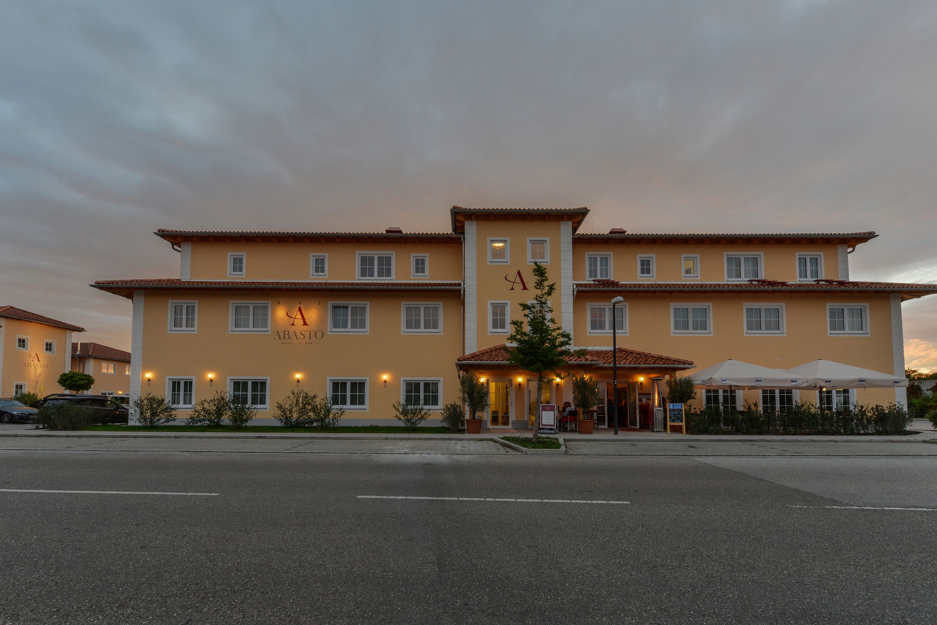 A two-story hotel with a central entrance, multiple windows, and outdoor seating.