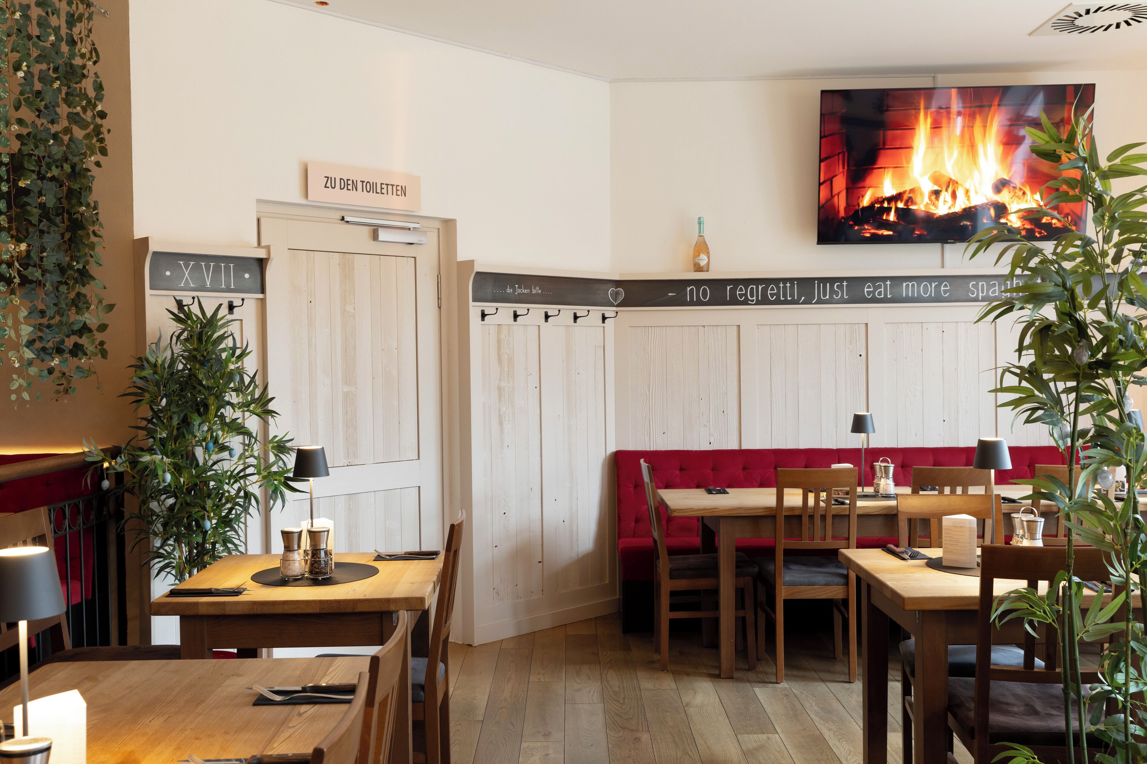 Interior de restaurante con mesas de madera, asientos tapizados en rojo y una chimenea.