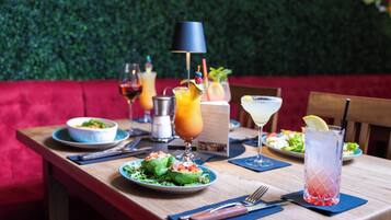 Une table à manger dressée avec différents plats et boissons, placée devant un mur vert et agrémentée de sièges rouges.