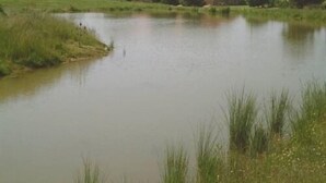 A calm body of water with a building in the background. - Glebe Farm Apartments (Market Rasen)