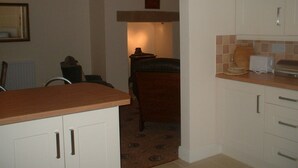 A kitchen with white cabinets, a wooden countertop, and a patterned rug. - Hamsteels Hall (Durham)