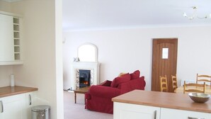 A compact living space with a kitchenette, a red sofa, a fireplace, and a dining area. - Hamsteels Hall (Durham)
