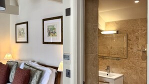 A hotel room with a bed, bedside table, lamp, and two framed pictures on the wall. - Top Joes Townhouse (Narberth)