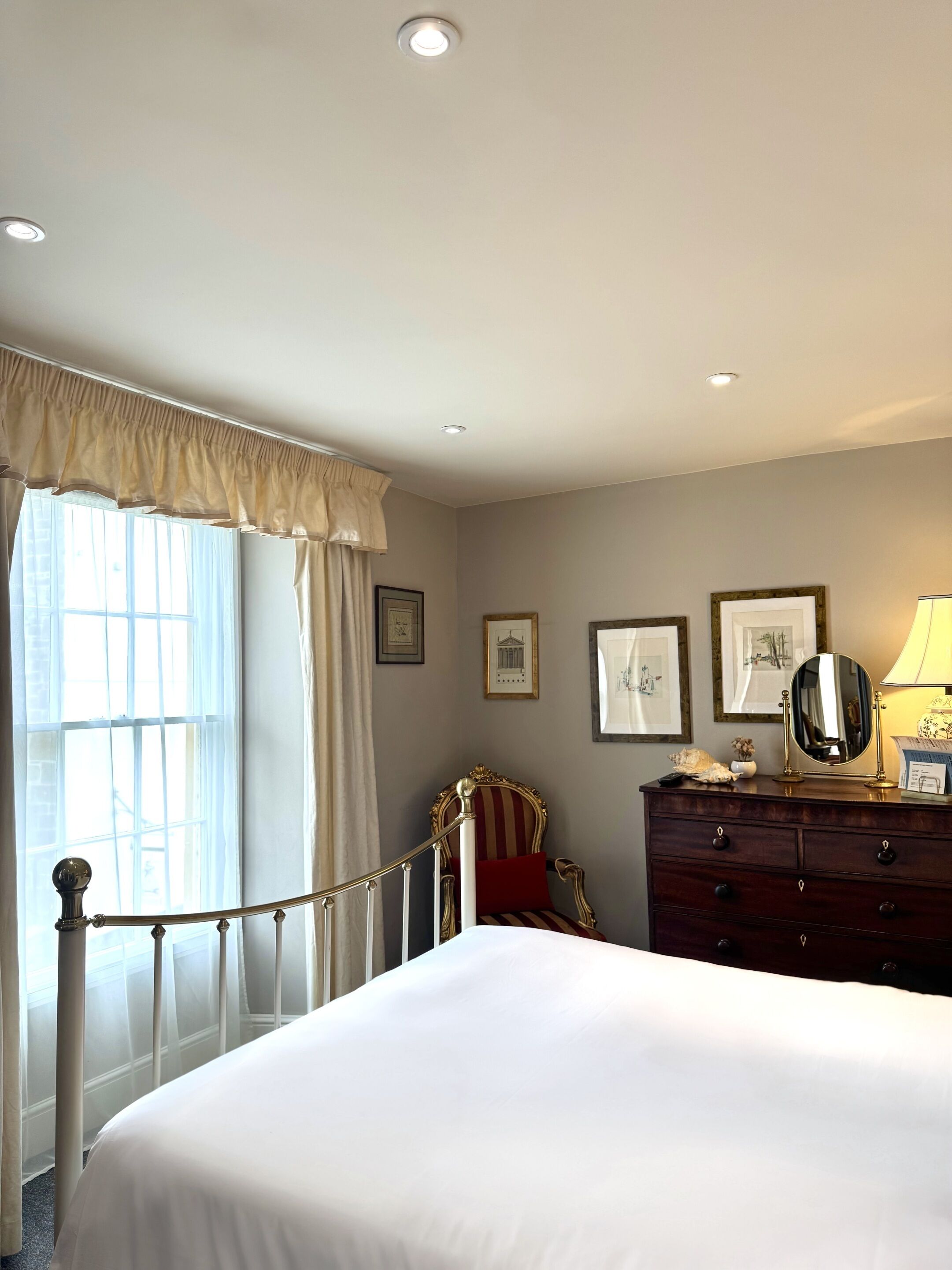 A hotel room with a large bed, a vanity with a mirror, and a chair.