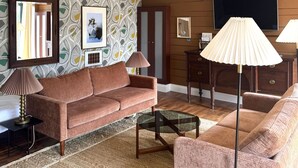 A living room with a brown sofa, a glass coffee table, and a patterned wallpaper. - Top Joes Townhouse (Narberth)