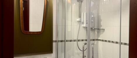 A bathroom with a glass-enclosed shower, a sink with a mirror, and a towel hanging on the wall.