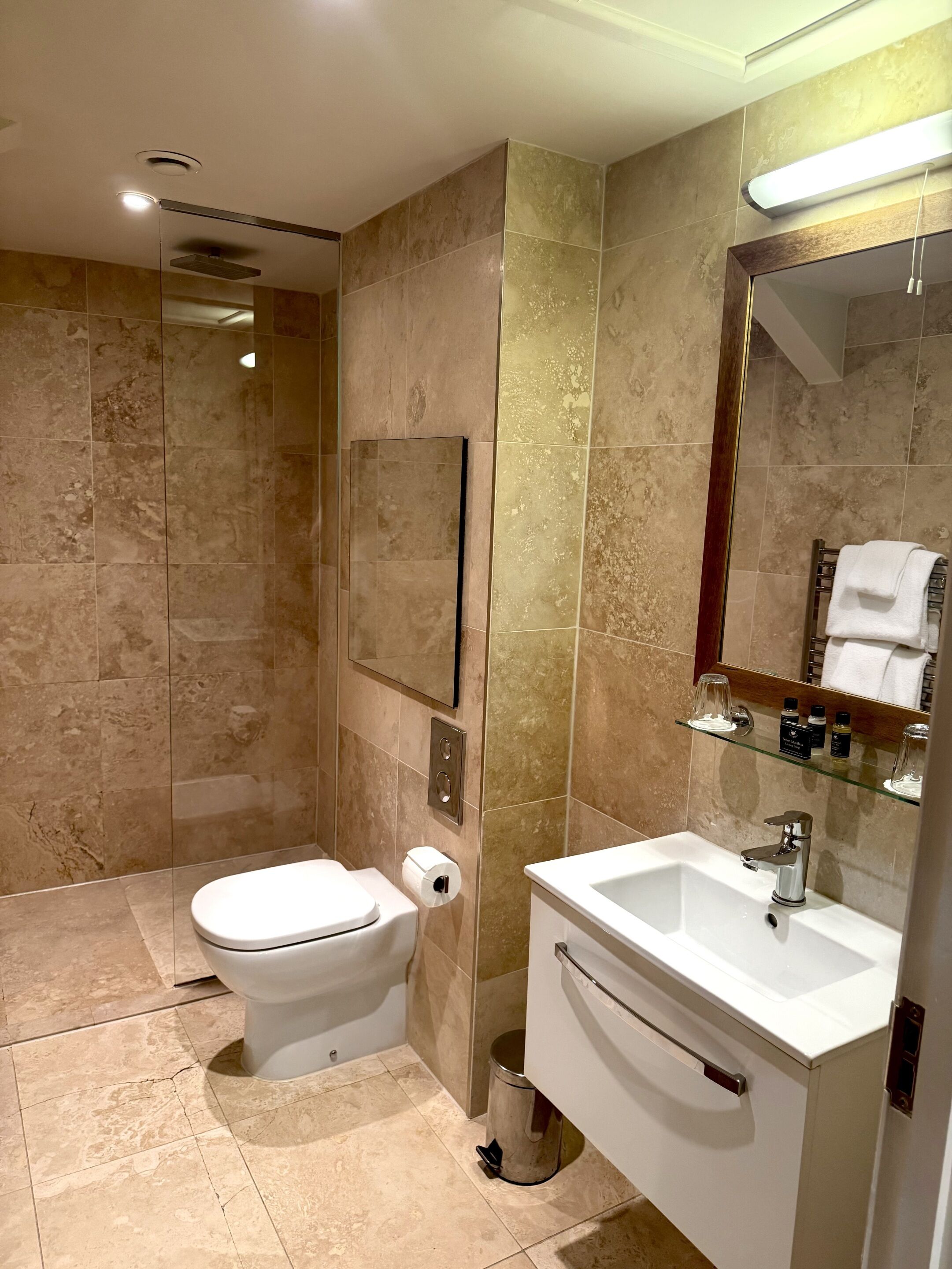 Une salle de bain moderne équipée de toilettes, d’un lavabo et d’une douche à parois de verre.