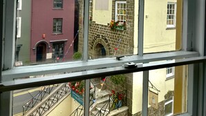 A view through a window of a building with a clock tower, a staircase, and flower boxes. - Top Joes Townhouse (Narberth)