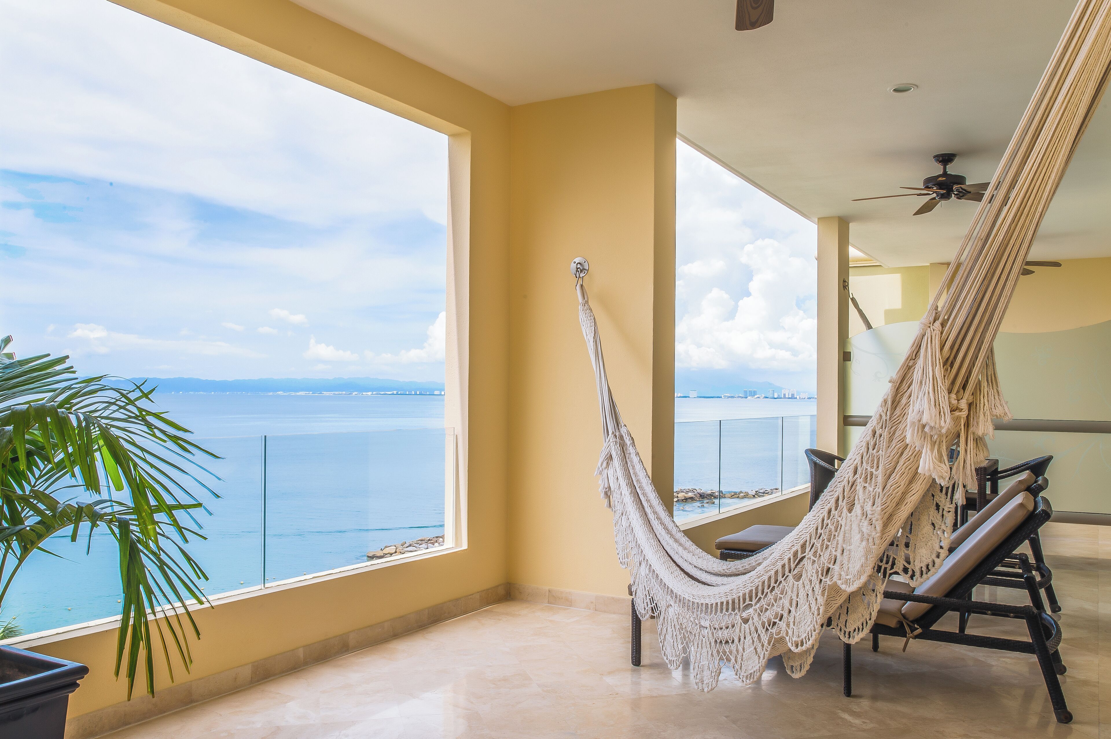 A hammock chair on a balcony with a view of the sea.