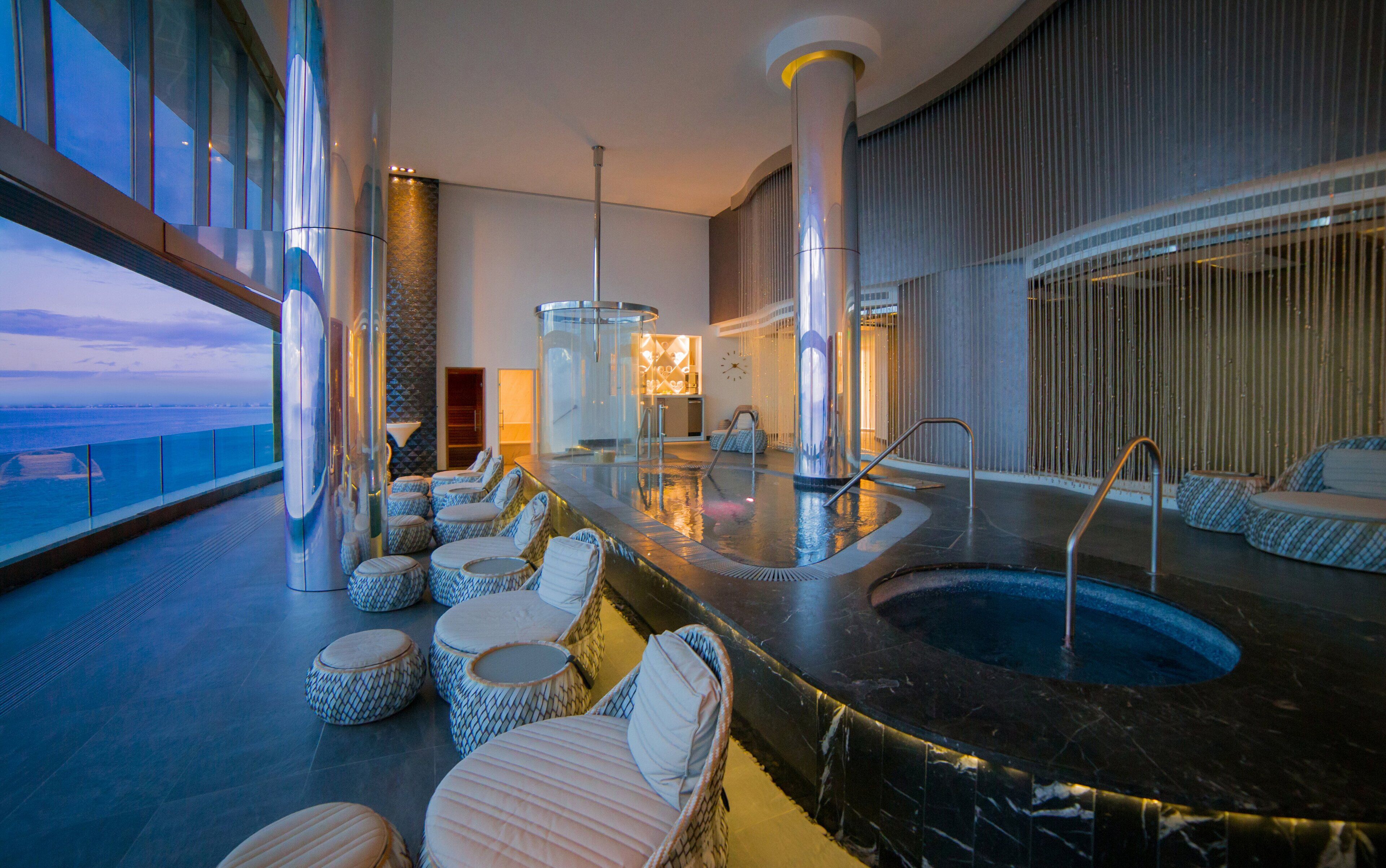 A luxurious indoor pool area with seating and a view of the ocean.
