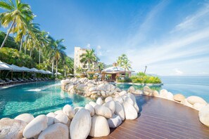 A resort pool area with a wooden deck, lounge chairs, and a building with a dome roof. - Garza Blanca Preserve Resort & Spa - All Inclusive (Puerto Vallarta)