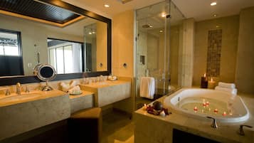 Un baño moderno con lavamanos dobles, un espejo grande, ducha con cerramiento de vidrio y una bañera con velas.