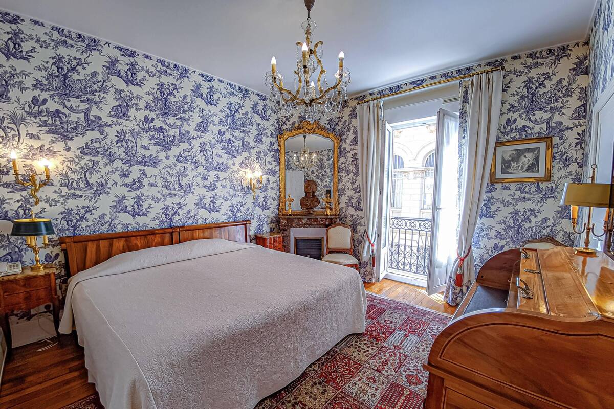 Ein Schlafzimmer mit einem großen Bett, einem hölzernen Schminktisch, einer Kandelaber und einem Kamin.